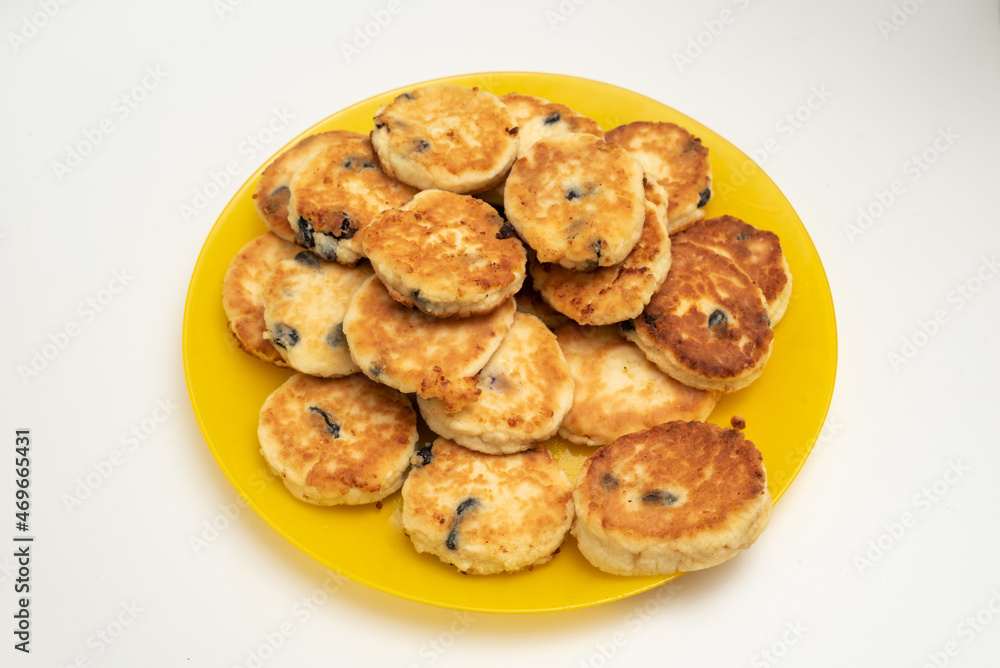 Full yellow plate of cottage cheese pancakes on white background