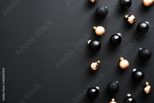 Black and bronze color Christmas balls decoration on dark background. Flat lay, top view, copy space. Minimal style.