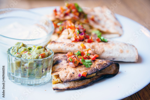 Delicious Mexican quesallidas made with chicken, tomato pieces and served with guacamole sauce.