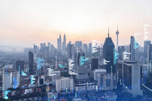 Glowing FOREX graph hologram, aerial panoramic cityscape of Kuala Lumpur at sunset. Stock and bond trading in KL, Malaysia, Asia. The concept of fund management. Double exposure.