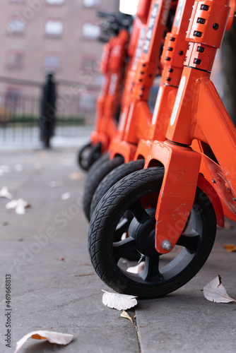 A close up shot of the front tyre of an orange electric scooter - parked in the city
