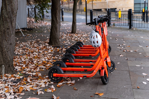 A row of orange electric scooters parked in a row