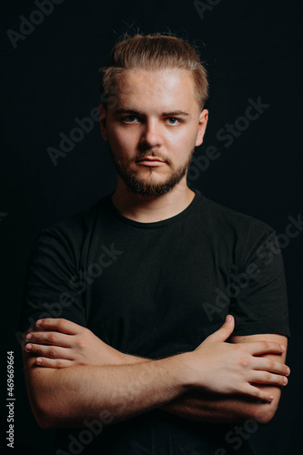Attractive stylish guy stands with arms crossed and looks in camera. Serious man with cute gentle facial expression ponders. Smart man with own opinion. Man develops idea. Business man.Studio shooting
