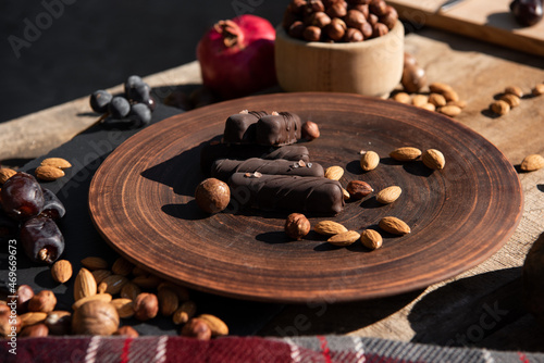 Chocolate, nuts, candy and teapot with cup of tea on the wooden table. Copy space. Close-up. Outside sunshine background.