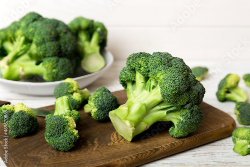 fresh green broccoli on wooden cutting board with knife. Broccoli cabbage leaves. light background. Flat lay