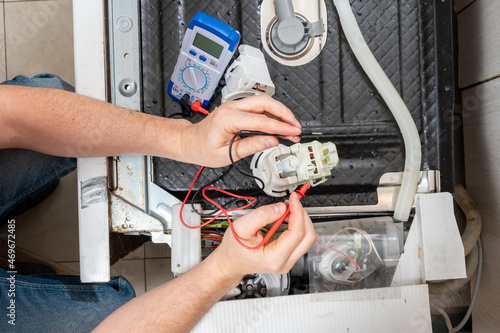 A man takes measurements with an electric tester of dishwasher parts