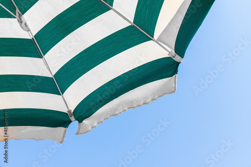 Part of the beach umbrella with white and green stripes in the middle of summer. Bottom view.