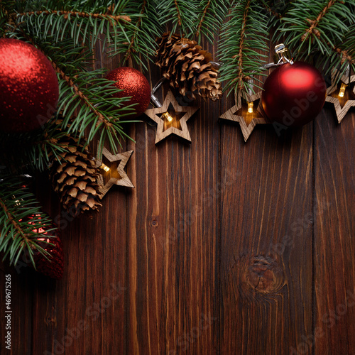 Christmas background with fir branches  cones  red baubles and star shape lights on dark wooden board. Top view. Copy space. Xmas decoration