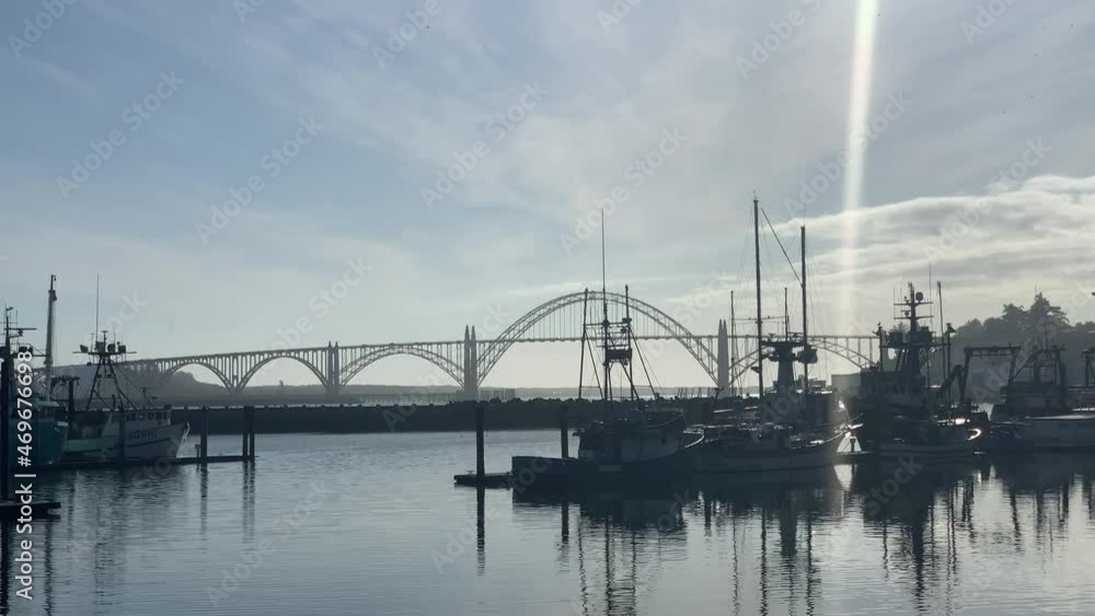 Boats At Port Of Newport With Yaquina Bay Bridge On A Sunny Day In Lincoln County, Oregon, United States. - wide shot Boats At Port Of Newport With Yaquina Bay Bridge On A Sunny Day In Lincoln County, Oregon, United States. - wide shot