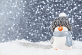 Christmas panorama background. Happy cute penguin in a winter hat on snowdrifts in the light of a lantern at night with hard shadows on the snow, and night bokeh. Christmas or New Year concept.