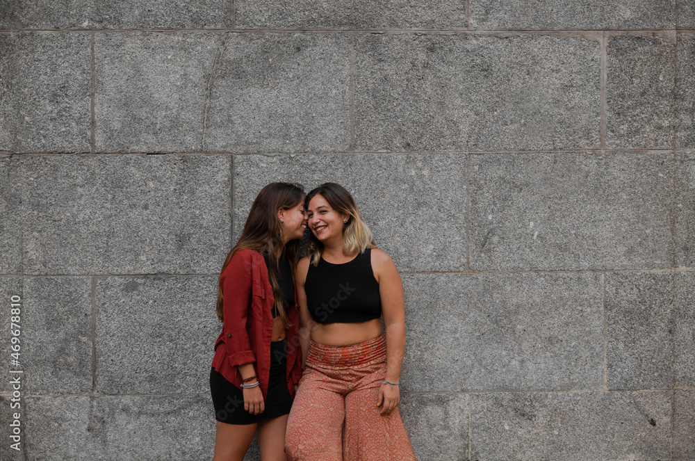 Portrait of two girls standing against stone wall