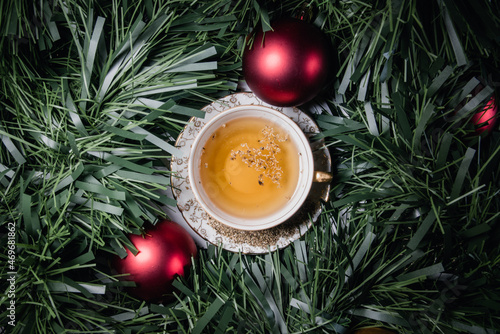Vista cenital de una taza llena de té de manzanilla caliente rodeada por un espumillón con adornos navideños photo