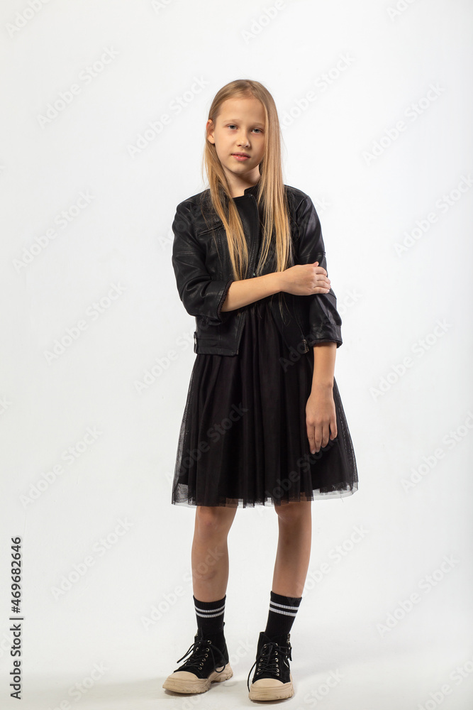 A full-length portrait of a young girl with long brown hair dressed in a hooligan style. A full-length portrait of a young girl with long brown hair dressed in a hooligan style.