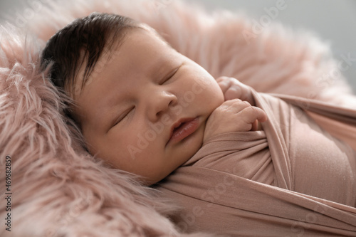 Cute newborn baby sleeping on fuzzy blanket, closeup