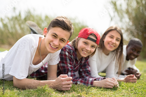 multinational modern teens lie in the park on the grass