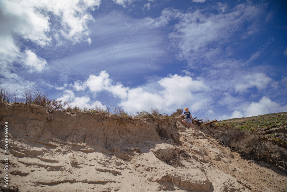 Boy climbing sand dune at Murrel's Beach in Portland, Australia