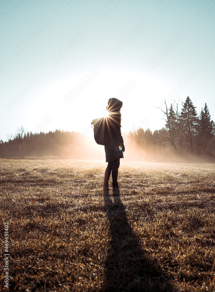 Girl standing in thick fog with a colorful morning sunlight. Human silhouette in different poses in autumn.
