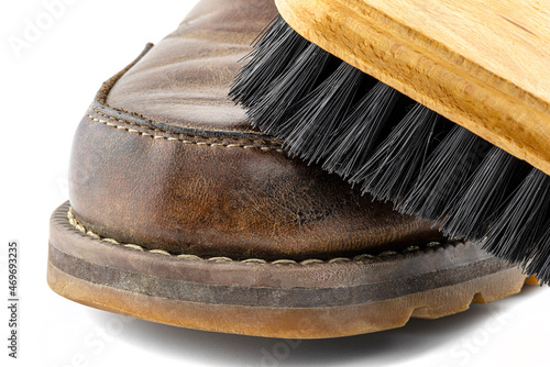Macro photo of an old brown leather booties polished with paste, shoe brush lies on the shoe, isolated on a white background.