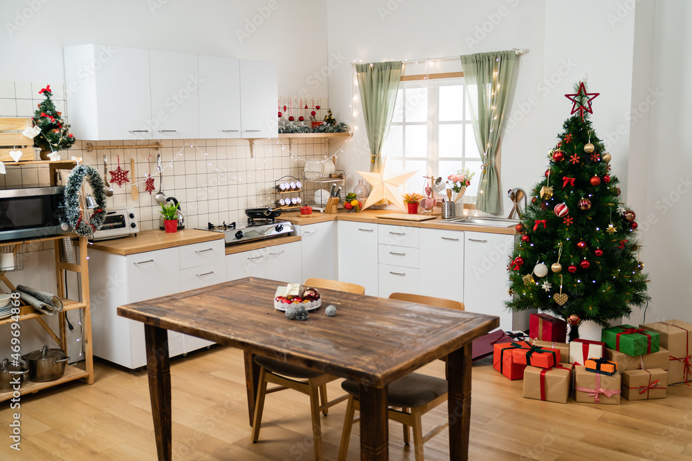 wide angle view of a cozy bright home kitchen interior with wood dining table and Christmas tree decorated for xmas winter holiday