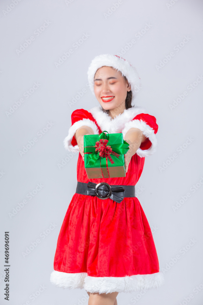 Asian girl in christmas dress holding gift box on white background