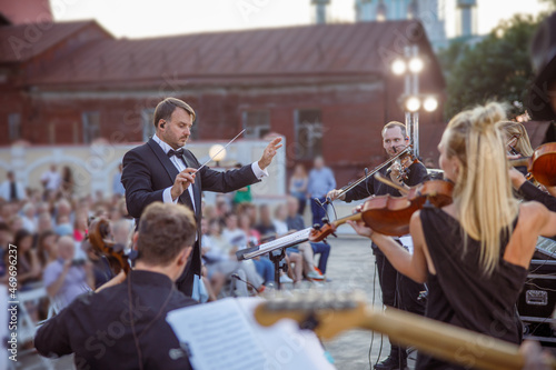 Photo Conductor directing orchestra performance on the street