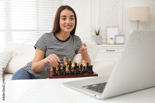 Young woman playing chess with partner through online video chat at home