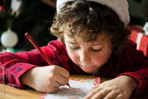 Caucasian kid writing a Christmas wishlist photo