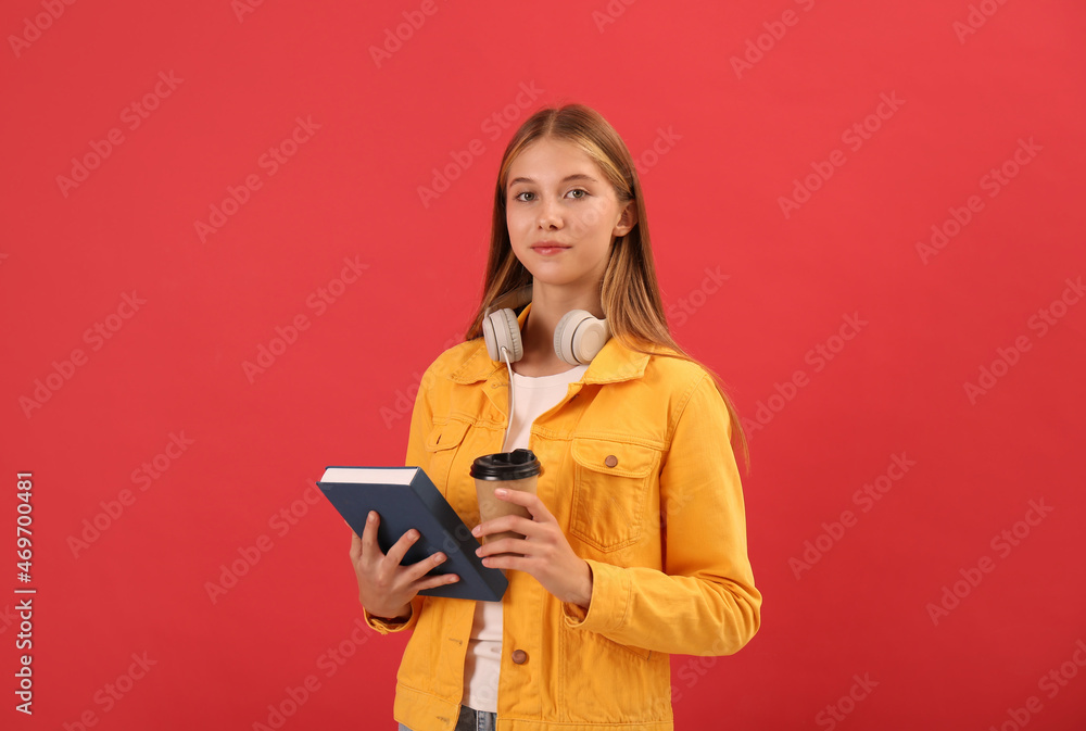 Teenage student with book, cup of coffee and headphones on red background Teenage student with book, cup of coffee and headphones on red background