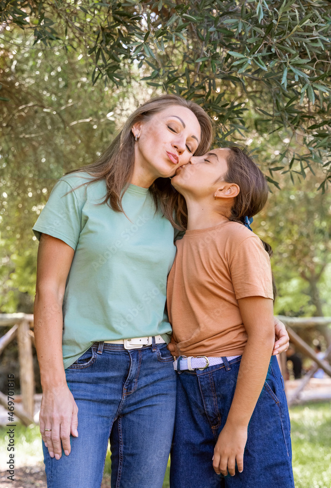Mother and daughter embracing each other and smiling in a park Mother and daughter embracing each other and smiling in a park