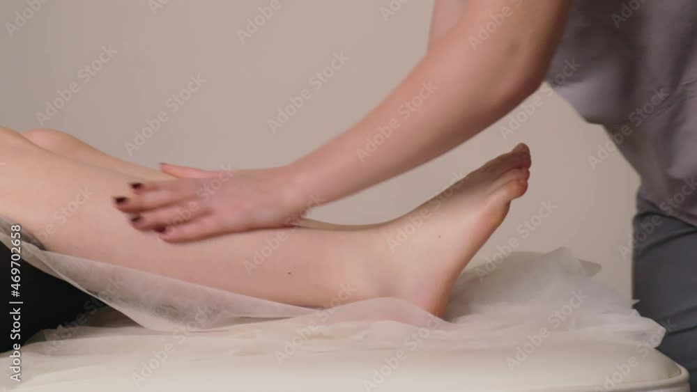 Woman masseur therapist kneading healthy legs feet massage relaxing professional therapy hands oil. Girl lying couch table resting gets rubdown spa salon body care concept slow motion treatment Woman masseur therapist kneading healthy legs feet massage relaxing professional therapy hands oil. Girl lying couch table resting gets rubdown spa salon body care concept slow motion treatment