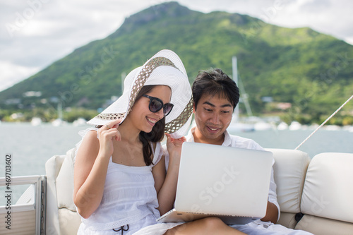 Two business people working with laptop on a sailing boat - sailing trip.