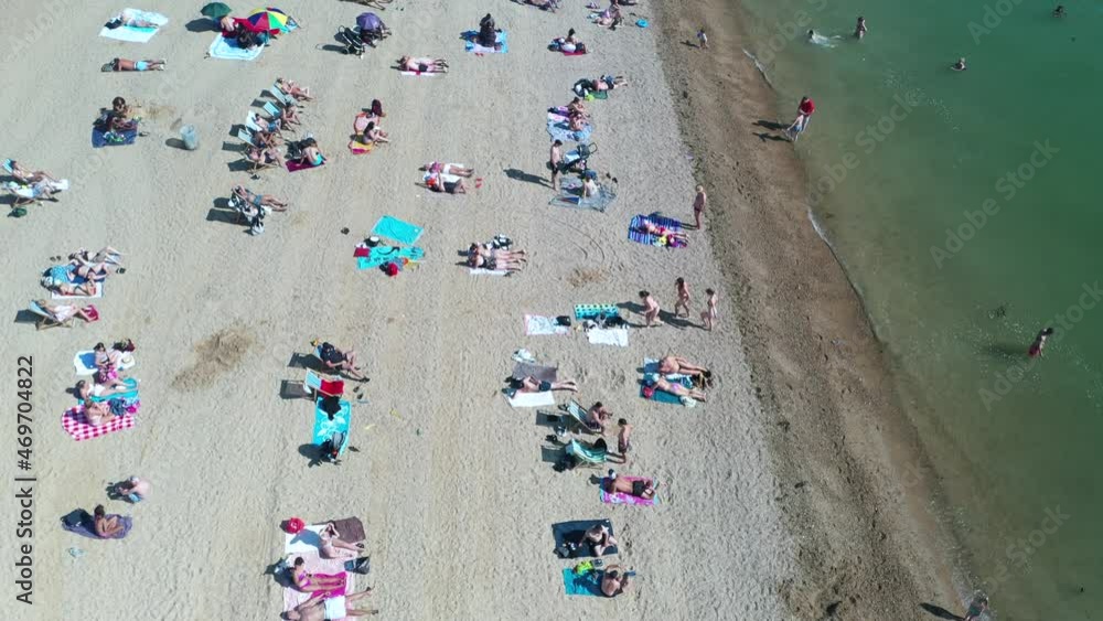 People sitting or laying on beach, stripe of sand along sea coast in town People sitting or laying on beach, stripe of sand along sea coast in town