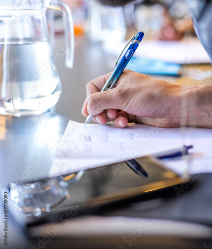 Mans hand taking notes at meeting. Hand writing with a pen.