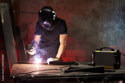 a masked welder works in a workshop from welding there are sparks photo