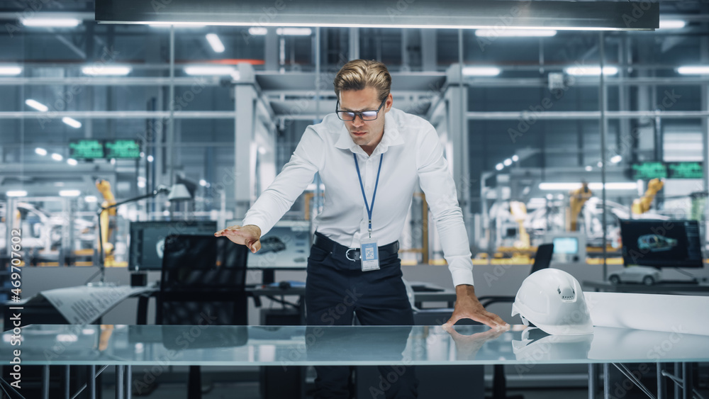 Confident Engineer in White Shirt Making Gestures of Moving Invisible Object in Virtual Reality in an Office at Car Assembly Plant. Industrial Specialist Working in Technological Development Facility. Confident Engineer in White Shirt Making Gestures of Moving Invisible Object in Virtual Reality in an Office at Car Assembly Plant. Industrial Specialist Working in Technological Development Facility.