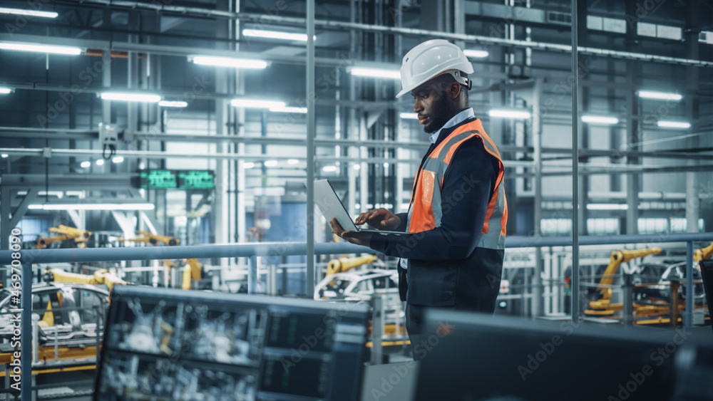 African American Engineer Using Laptop and Looking Out of the Office at a  Car Assembly Plant. Vehicle Factory Line Operator Working on Computer,  Overviewing Autonomous Electric Car Production. Stock Photo | Adobe