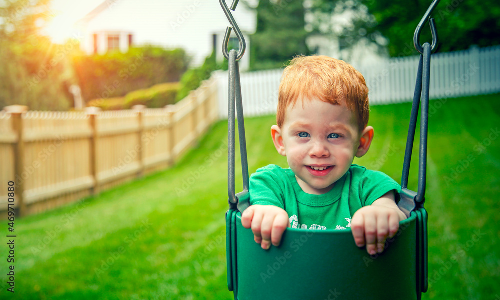 Cute little boy sitting in swingset at sunset Cute little boy sitting in swingset at sunset