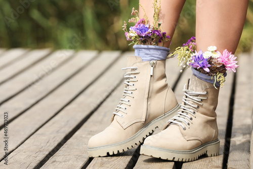 Woman standing on wooden pier with flowers in socks outdoors, closeup. Space for text photo