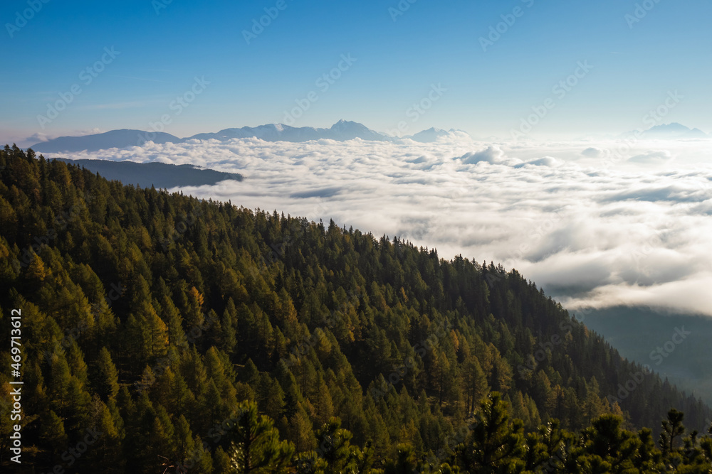 Sunrise on top of a mountain with view into misty valley with fog.