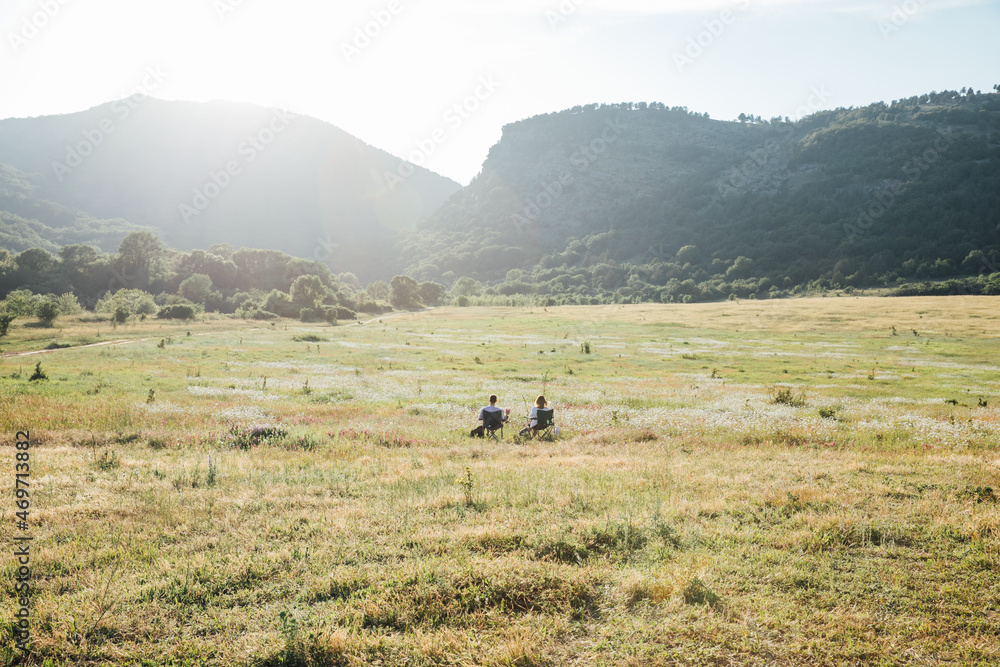 two people sitting in a chair looking at the mountain landscape two people sitting in a chair looking at the mountain landscape