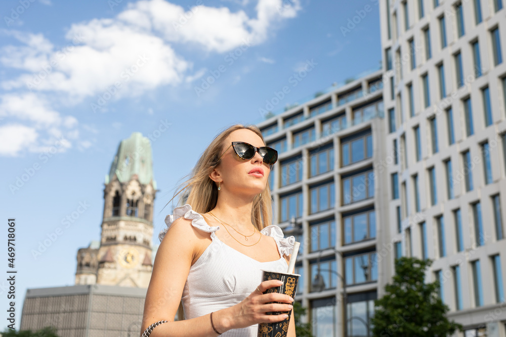 wunderschöne Frau in der City Berlin im Weißen Kleid und Sonnenbrille erlebt einen digitalen Tag voller Lifestyle