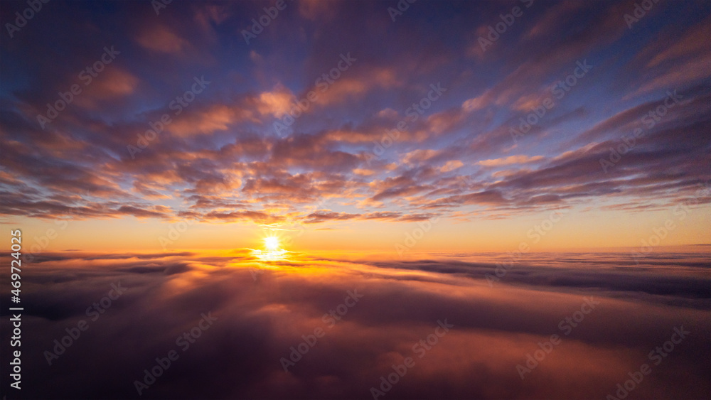 Drone photo of setting sun above clouds in the sky. Dramatic drone photo flying high in the clouds