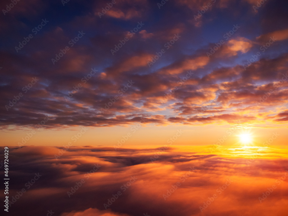 Beautiful landscape of setting sun from the sky. Dramatic sunset from the plane above bright clouds