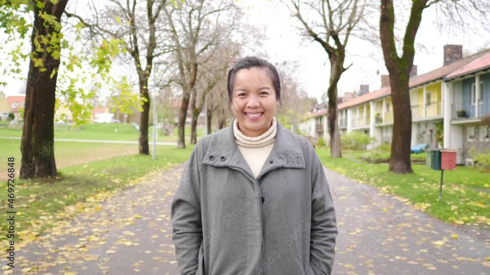Front view of Asian woman standing at the park, smiling and looking at camera. Autumn season, leaves falling from the trees , beautiful nature, getting some fresh air at the park, Sweden Front view of Asian woman standing at the park, smiling and looking at camera. Autumn season, leaves falling from the trees , beautiful nature, getting some fresh air at the park, Sweden
