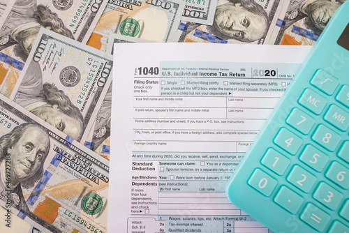 Tax form 1040 with a calculator on a money background.