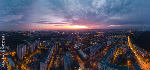 Aerial sunset scenic vibrant panorama wide view on Kharkiv city, Pavlove pole. Night lights on streets of residential district and cloudy purple sky. Cars driving moody illuminated streets