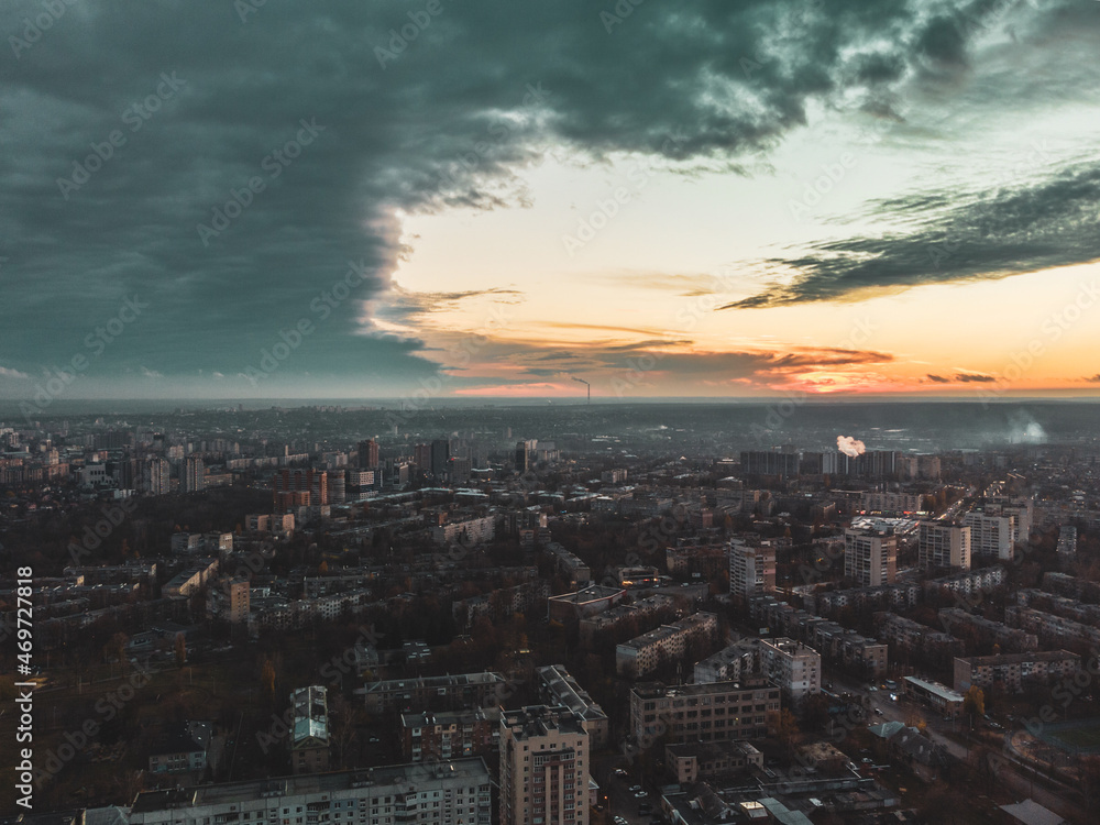 Aerial sunset evening view on residential Kharkiv city Pavlove Pole district. Multistory buildings with scenic cloudy sky and orange sun on horizon. Color graded