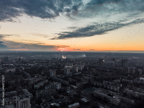 Aerial sunset evening view on residential Kharkiv city Pavlove Pole district. Gray multistory buildings with scenic bright orange cloudy sky on horizon