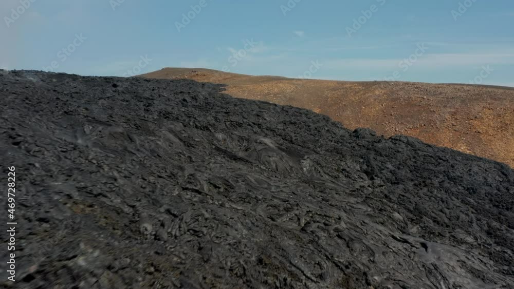Fly over dark stripe of cooling volcanic material. Solidified lava stream after eruption. Fagradalsfjall volcano. Iceland, 2021 Fly over dark stripe of cooling volcanic material. Solidified lava stream after eruption. Fagradalsfjall volcano. Iceland, 2021