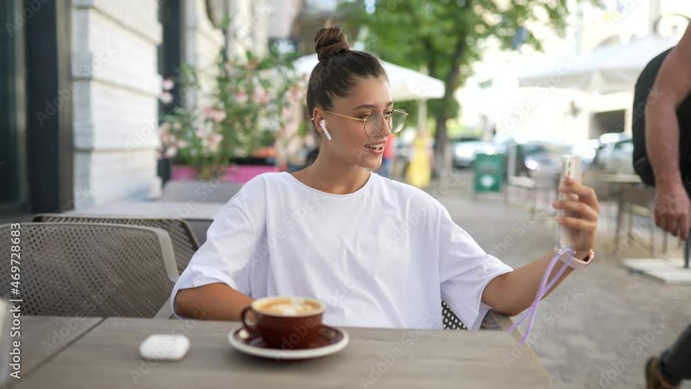 beautiful young woman sitting in street cafe using a smartphone beautiful young woman sitting in street cafe using a smartphone